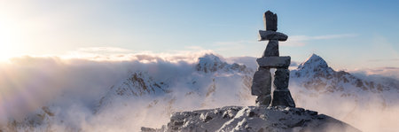 Rock Statue, Inuksuk, on top of a Snow Covered Mountain Top. 3d Rendering Art. Aerial Image Background from British Columbia, Canada.の写真素材