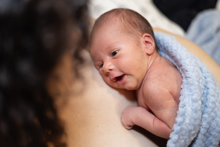 Adorable Newborn Baby Boy sitting on mother chest. Skin to Skin. Lookingの写真素材