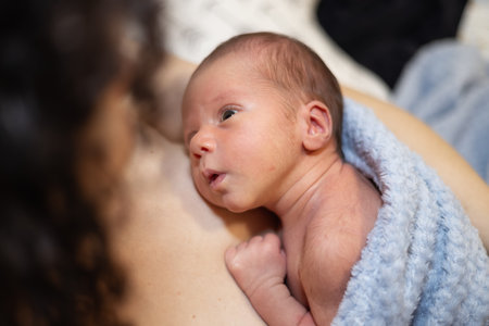 Adorable Newborn Baby Boy sitting on mother chest. Skin to Skin. Lookingの写真素材