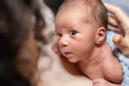 Adorable Newborn Baby Boy sitting on mother chest. Skin to Skin. Lookingの写真素材
