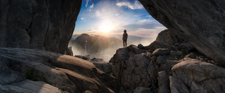 Adventurous Woman Standing in cave on top of Mountain. Extreme Adventure Composite. 3d Rendering Peak. Background Aerial Image from British Columbia, Canada.の写真素材