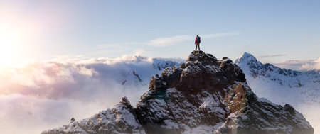 Adventurous Man Standing on top of Mountain Cliff. Dramatic Extreme Adventure Composite. 3d Rendering Peak. Background Aerial Image from British Columbia, Canada.の写真素材