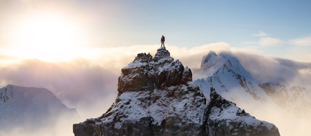 Adventurous Man Standing on top of Mountain Cliff. Dramatic Extreme Adventure Composite. 3d Rendering Peak. Background Aerial Image from British Columbia, Canada.の写真素材