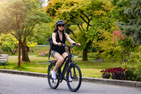 Fit Caucasian Woman riding an Electric Bicycle on a trail in Stanley Park, Downtown Vancouver, British Columbia, Canada.の写真素材