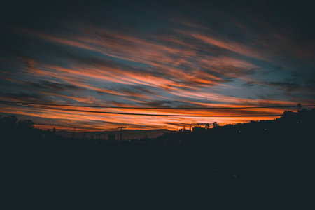 Sunset in the city with red clouds and silhouette of the cityの写真素材