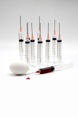 Eggs and syringe on white background photoの写真素材