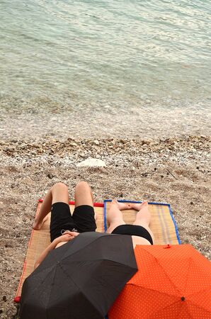 umbrella on beach with two people from behindの写真素材