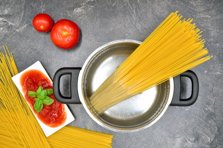 cooking spaghetti in pot with tomato close upの写真素材