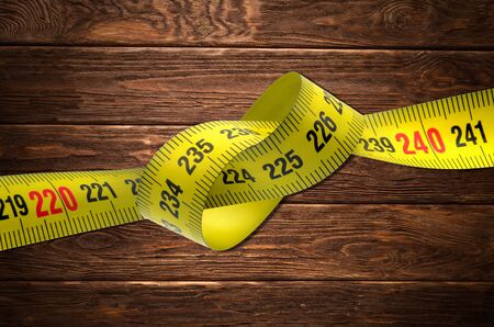 tangled tape measure with wood backgroundの写真素材