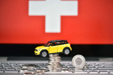 Miniature toy car on the background of the flag of Switzerland.の写真素材