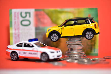 Toy car on coins with a police car on the background.の写真素材