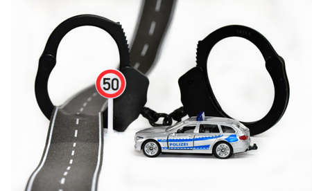Toy police car and handcuffs on a white background. The concept of stopping crime.の写真素材