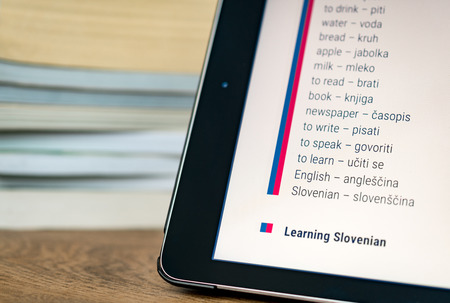 Learning Slovenian using a tablet with books in the background.の写真素材