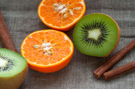 Fruit set - orange tangerine half,  kiwi and cinnamon sticks on hessian linen fabric clothの写真素材