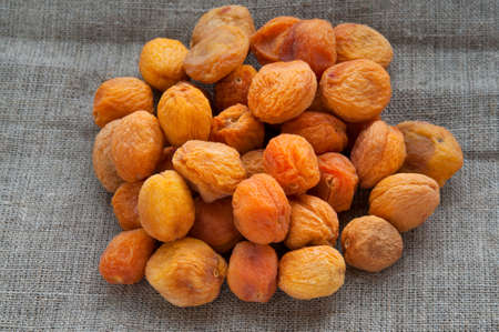 Heap of dried apricots on hessian linen fabric clothの写真素材