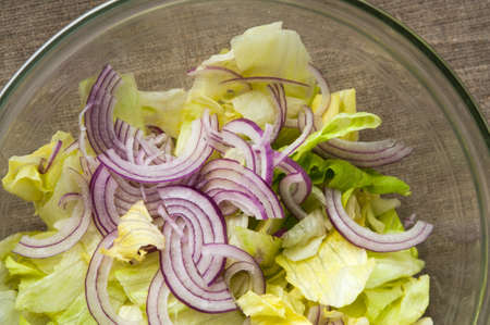 Fresh vegetable salad with onion in transparent bowl on linen clothの写真素材