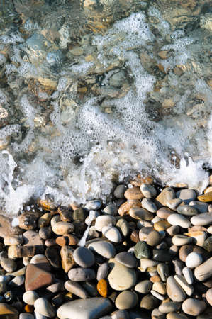 Top view of sea wave over gravel or pebble closeup