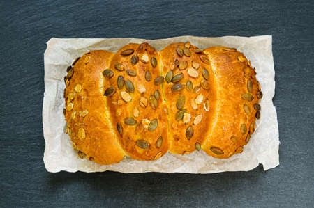Rustic home made bread loaf with pumpkin seeds on black slate stone board