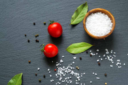 Food ingredients: tomatoes, bay laurel leaves and salt on black slate stone . Top flat viewの写真素材