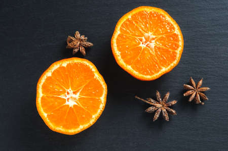 Top flat view: tangerine half and anise stars on black slate stone surfaceの写真素材