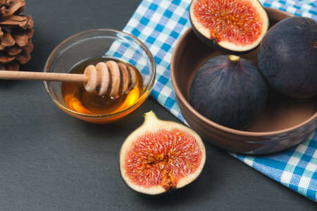 Ceramic bowl with fresh riped figs and honey on rustic black stone surfaceの写真素材