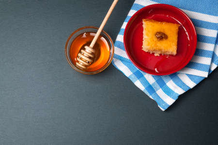 Small glass bowl of natural honey with stick and sweet cake. On the black stone rustic table.の写真素材