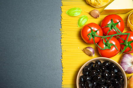Top view: pasta or italian spaghetti with ingredients on black stone slate background. Copyspace