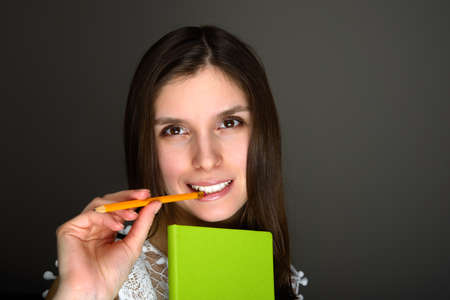 Portrait of young brunette female chewning pencil