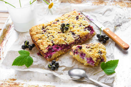 Black currant and cottage crumble cake on baking paper and rustic backgroundの写真素材