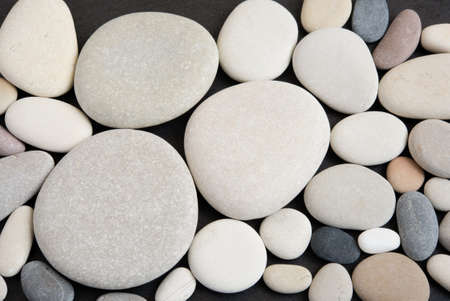 Top view of arranged pebble stones on black background