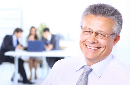 Portrait of a confident senior business man at meeting colleagues sitting at the back 