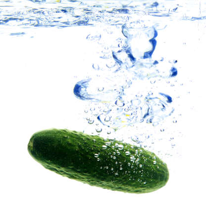 A background of bubbles forming in water after green cucumber are droppedの写真素材