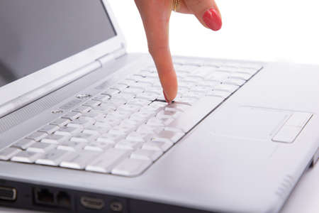 Finger pointing to a keypad of a laptop computer 