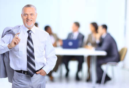 Successful business man standing with his staff in background at office 
