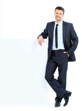 Portrait of happy smiling young business man showing blank signboard, isolated over white background の写真素材
