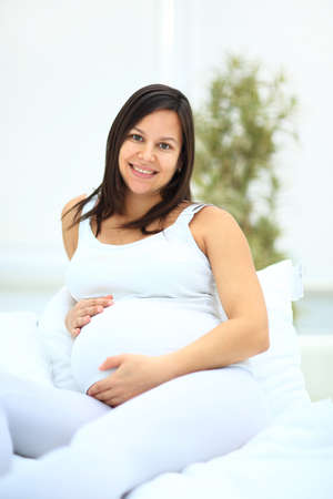 portrait of happy woman in a white dress, which waits for the childの写真素材
