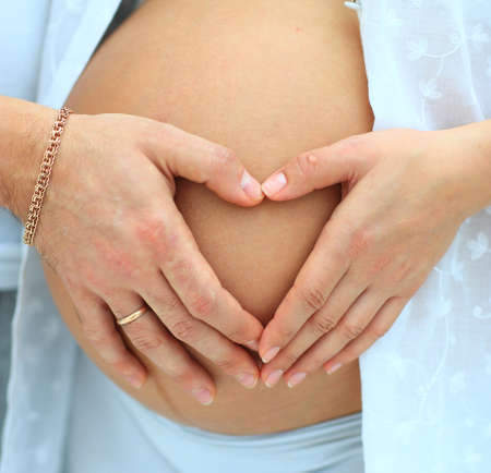 close-up image of the heart by mom's and dad's handson her babu bump