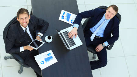 Team sitting behind desk, checking reports, talking. Top Viewの写真素材