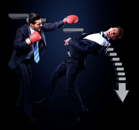 Two young businessman boxing againts dark background