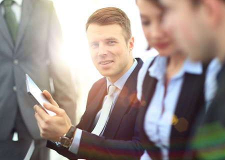 businessman posing in the meeting room while colleagues are working behindの写真素材
