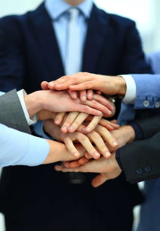 Close-up of business partners making pile of hands at meeting
