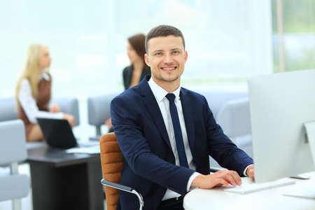 Handsome modern businessman holding at the computer with colleague on background