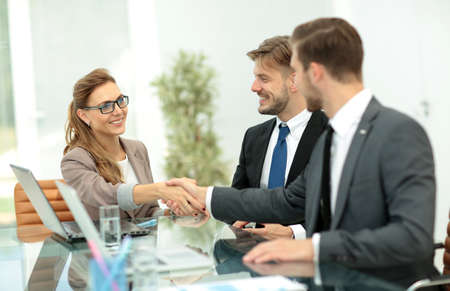Happy business partners shaking hands in an office
