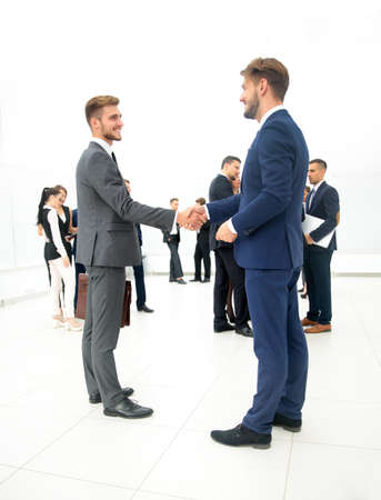 Two businessmen making agreement, their colleagues standing near byの写真素材