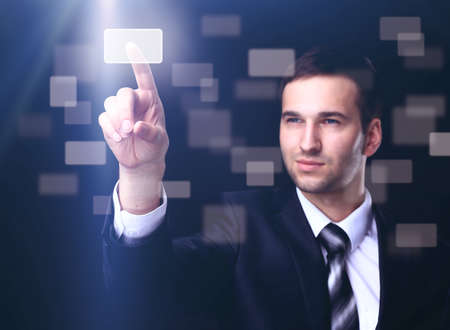 business man pressing a touchscreen button on dark backgroundの写真素材