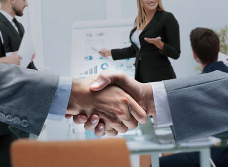 closeup of business handshake after signing the financial contract on background of business team...