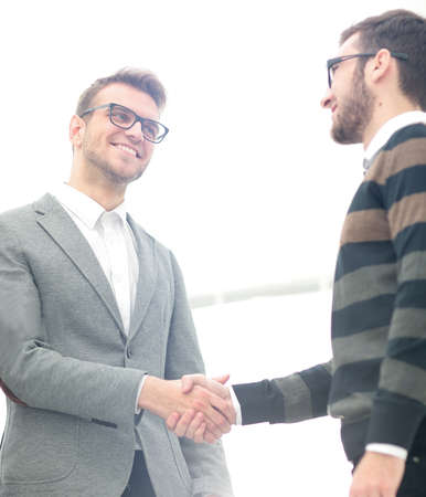Two men shaking hands and looking at each other with smileの写真素材