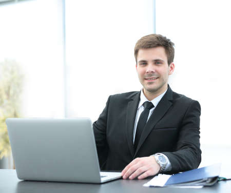 successful businessman sitting behind a Desk with an open laptop