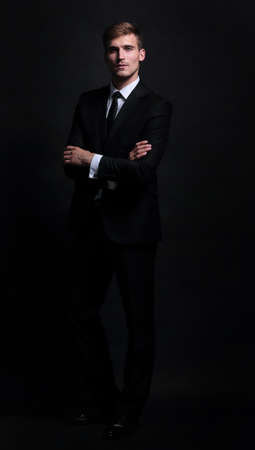 Full-length portrait of business man  with arms crossed isolated  on black backgroundの写真素材