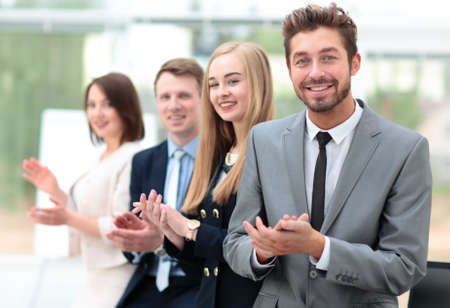 Business colleagues looking at camera and applauding in the offi